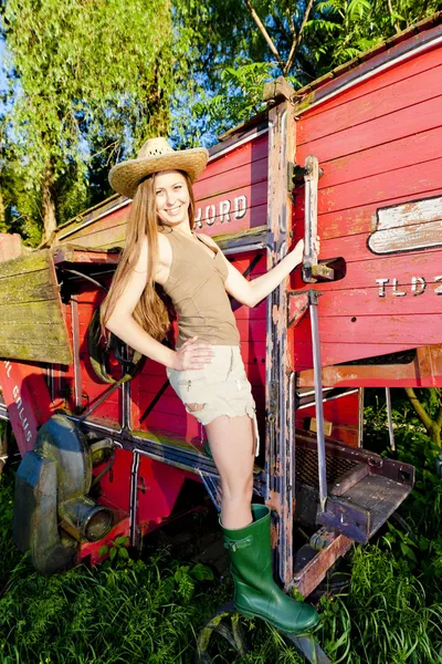 Ung kvinna som står vid gamla tröskverk — Stockfoto