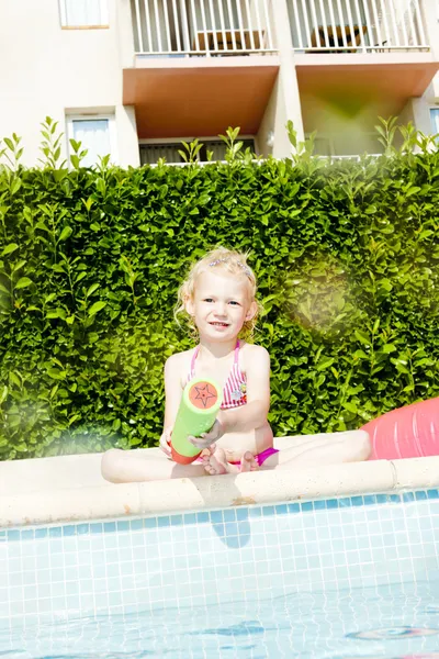 Bambina con spruzzatore d'acqua a bordo piscina — Foto Stock
