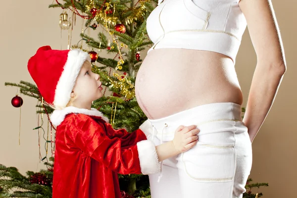 Kleines Mädchen und ihre schwangere Mutter zu Weihnachten — Stockfoto