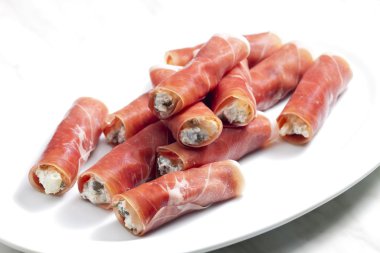 Parma ham rolls filled with cream cheese, Galia melon and capers clipart