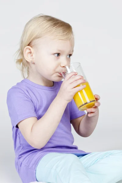 Портрет маленькой девочки, пьющей апельсиновый сок — стоковое фото
