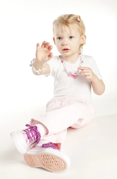 Sitting little girl wearing necklace — Stock Photo, Image