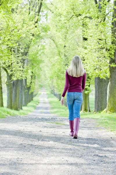 Vrouw dragen van rubber laarzen in voorjaar steegje — Stockfoto