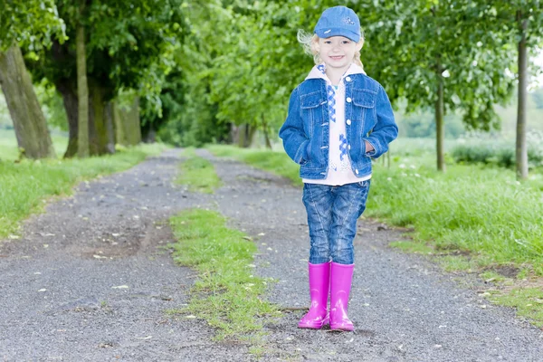 Kleines Mädchen mit Gummistiefeln in der Frühlingsgasse — Stockfoto