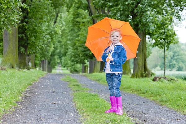 Little girl with umbrella in spring alley — Stock Photo, Image