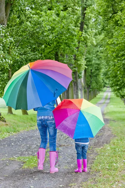 Anya és lánya esernyővel a tavaszi sikátorban — Stock Fotó