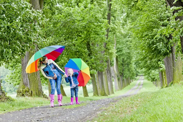 Mutter und Tochter mit Regenschirmen in der Frühlingsgasse — Stockfoto
