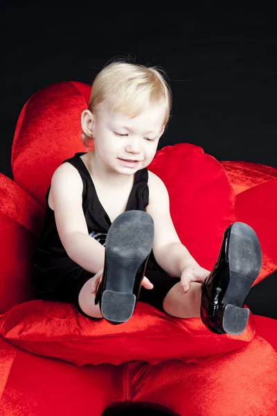 Little girl sitting on red armchair — Stock Photo, Image