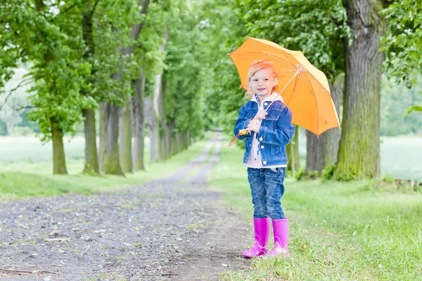 Holčička s deštníkem v jarní ulici — Stock fotografie