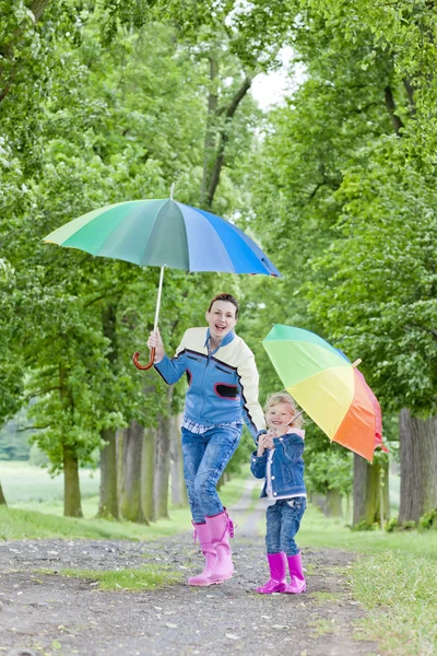 Matka i jej córka z parasolkami w wiosennej alejce — Zdjęcie stockowe
