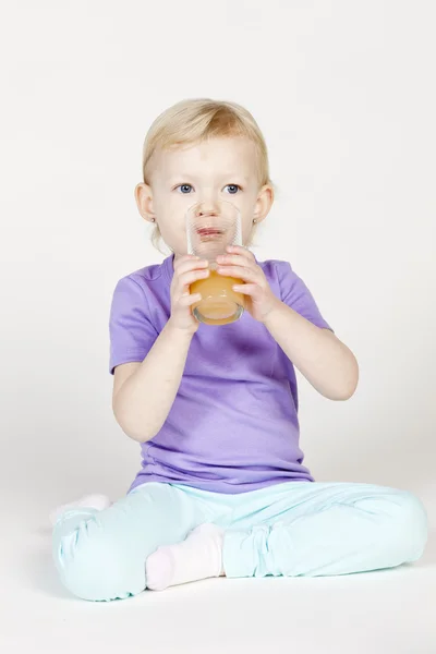 Liten flicka dricker apelsinjuice — Stockfoto