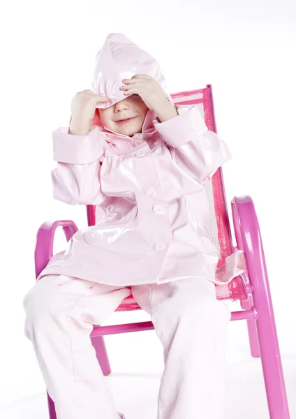 Menina vestindo capa de chuva sentado na cadeira — Fotografia de Stock