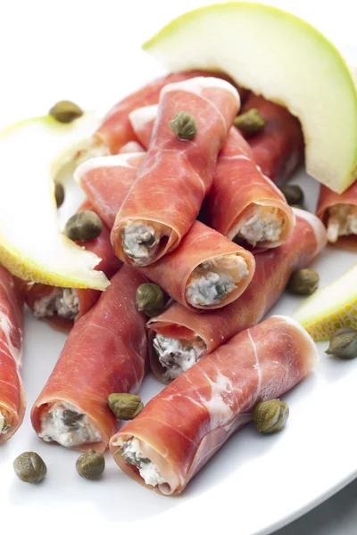 Parma ham rolls filled with cream cheese, Galia melon and capers — Stock Photo, Image