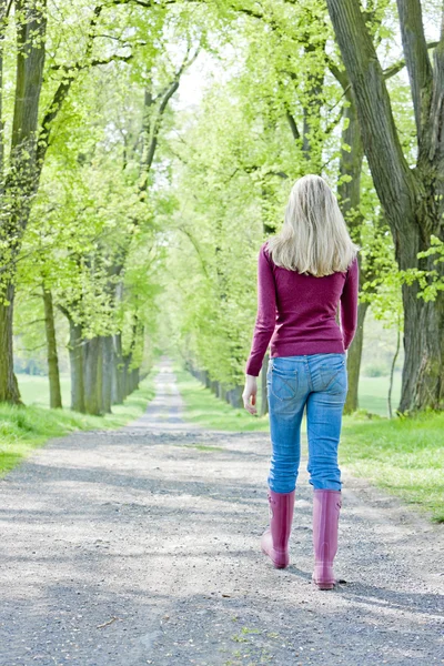 Žena nosí gumové boty v jarní ulici — Stock fotografie