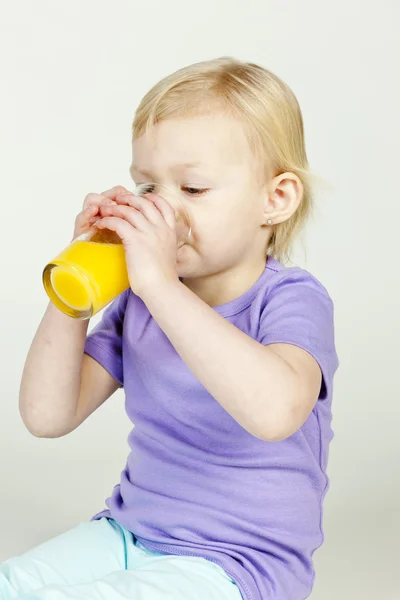 Porträt eines kleinen Mädchens, das Orangensaft trinkt — Stockfoto