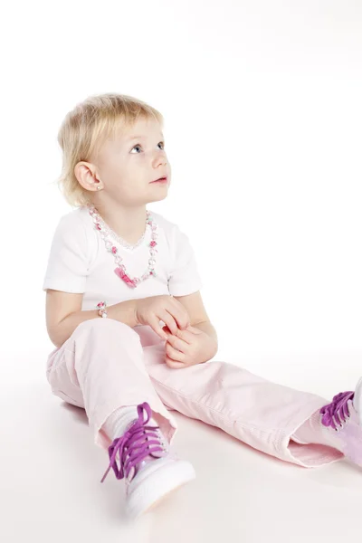 Sitting little girl wearing necklace — Stock Photo, Image