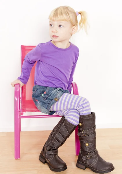 Kleines Mädchen mit Stiefeln auf Stuhl sitzend — Stockfoto