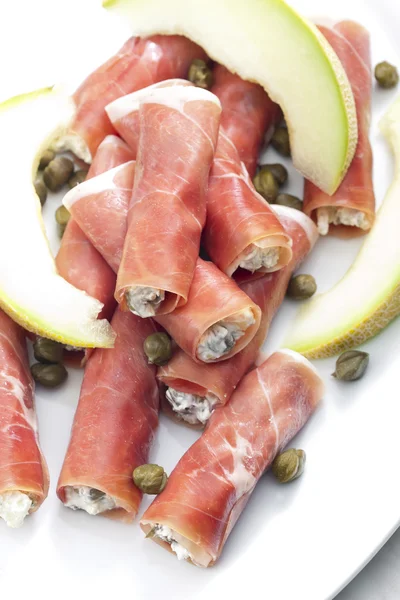 Parmaskinka rullar fyllda med färskost, galia melon och kapris — Stockfoto