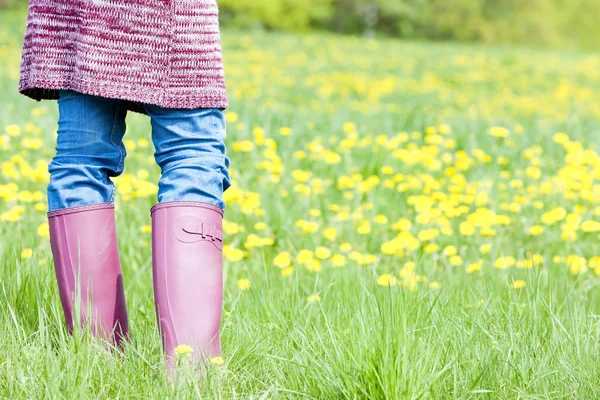 Detail of woman wearing rubber boots on spring meadow — Stock Photo, Image
