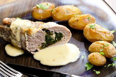 Baked pork tenderloin filled with spinach and goat cheese on cre clipart