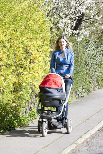 Woman with a pram on spring walk — Stock Photo, Image
