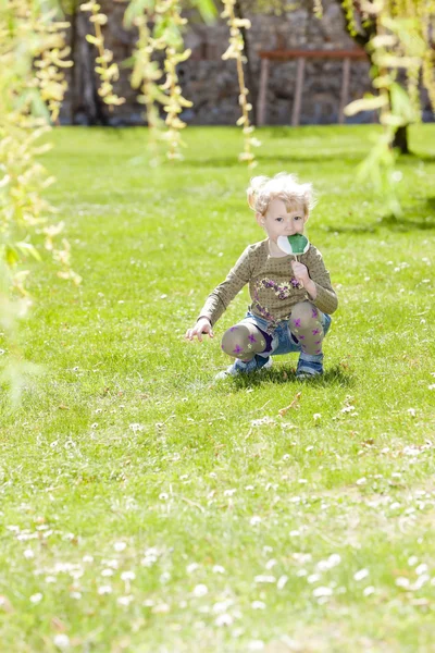 Bambina con un lecca-lecca seduta sull'erba — Foto Stock