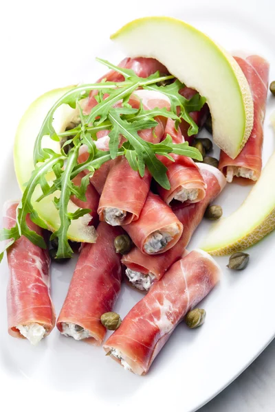 Parma ham rolls filled with cream cheese, Galia melon and capers — Stock Photo, Image