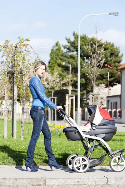Mulher com um carrinho de bebê no passeio de primavera — Fotografia de Stock