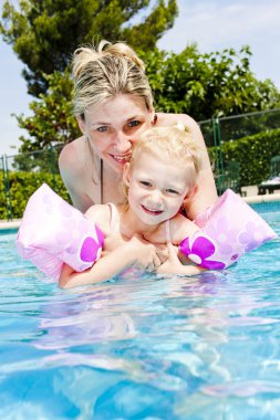 Mother with her daughter in swimming pool clipart