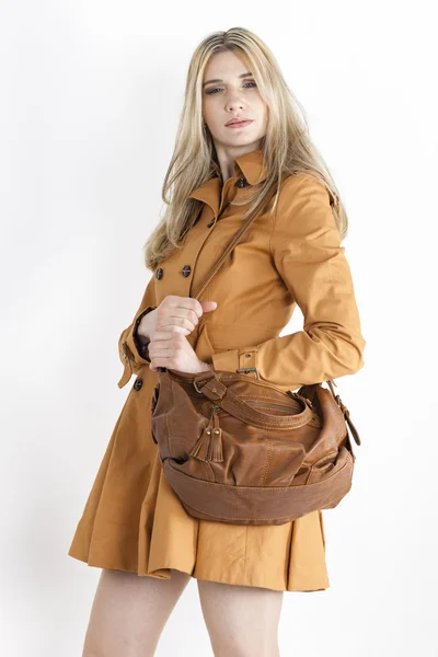 Retrato de mujer de pie con abrigo marrón con un bolso de mano —  Fotos de Stock