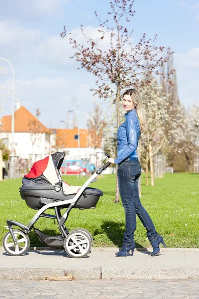 Kvinna med barnvagn på vår promenad — Stockfoto