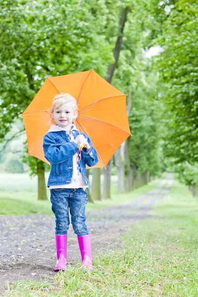 Little girl with umbrella in spring alley — Stock Photo, Image