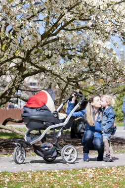 Mother and her daughter with a pram on spring walk clipart