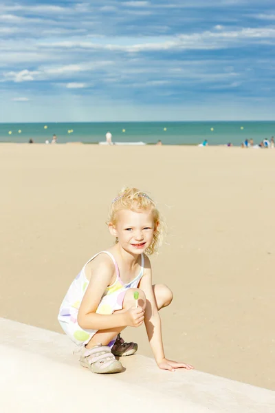 Little girl with a lollipop on the beach at sea — Stock Photo, Image