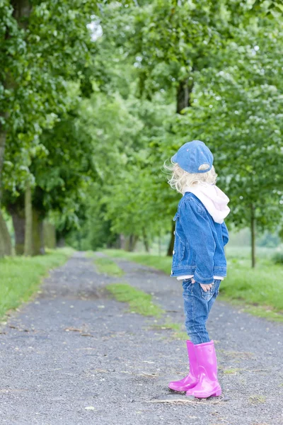 Menina vestindo botas de borracha no beco da primavera — Fotografia de Stock