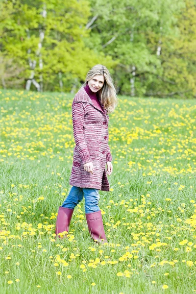 Mulher usando botas de borracha em pé no prado da primavera — Fotografia de Stock