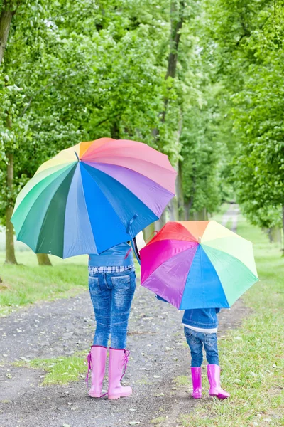 Mother and her daughter with umbrellas in spring alley Stock Photo