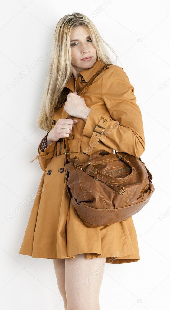 Portrait of standing woman wearing brown coat with a handbag