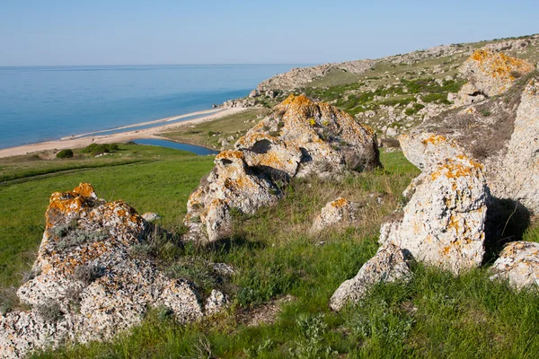 Stenar på grön kulle nära havet — Stockfoto