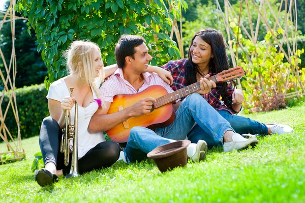 Молодые друзья играют на гитаре и трубе — стоковое фото