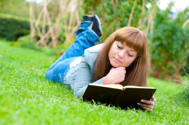 genç kadın çim üzerinde yalan bir kitap okuma