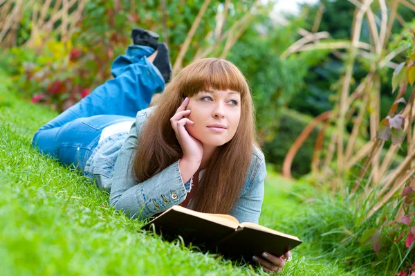 Mujer joven leyendo un libro tumbado en la hierba —  Fotos de Stock