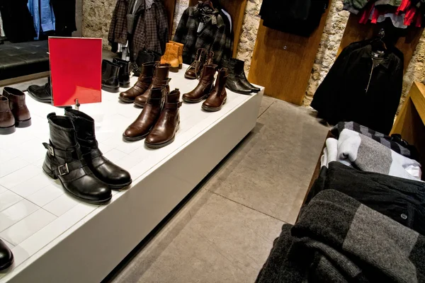 Muchos zapatos y ropa en los estantes de la tienda — Foto de Stock