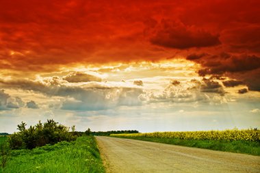 kırsal road, güneş ışınları ve dramatik bulutlu gökyüzü