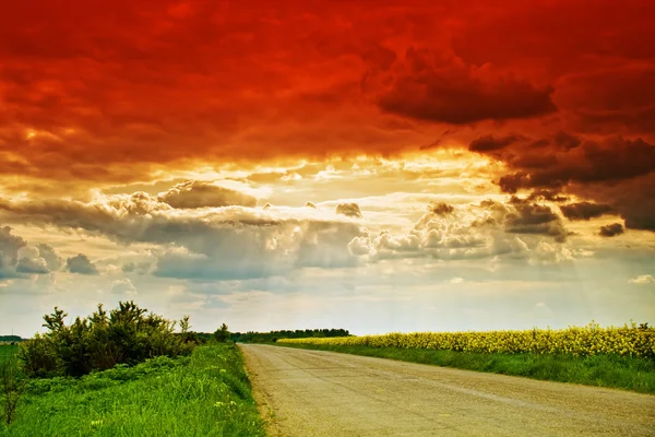 Lantlig väg, solen strålar och dramatiska molnig himmel — Stockfoto