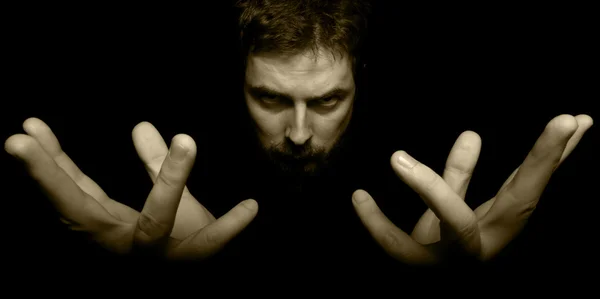 Mãos e rosto do mágico do mal no escuro — Fotografia de Stock