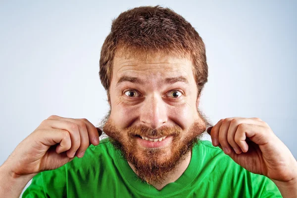 Grappige Dom mens grijpen zijn harige baard — Stockfoto