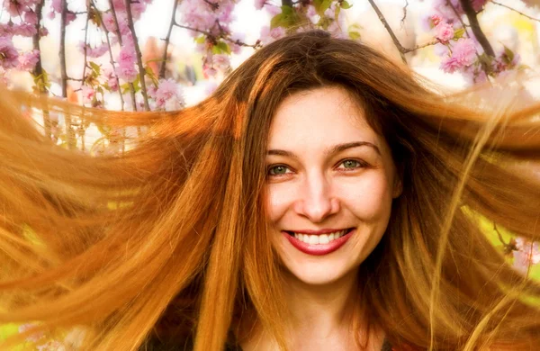 Šťastná žena s krásné dlouhé vlasy a květiny — Stock fotografie