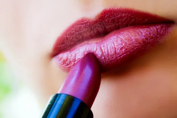 Vista macro de labios femeninos y lápiz labial rojo —  Fotos de Stock