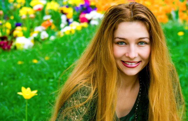 Mladá žena a květiny v pozadí — Stock fotografie